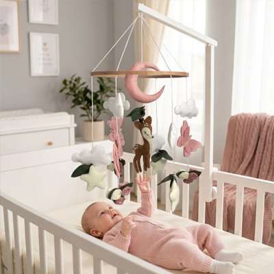 Mobile bébé en bois naturel avec figurines en feutre rose suspendues au-dessus d'un lit de bébé
