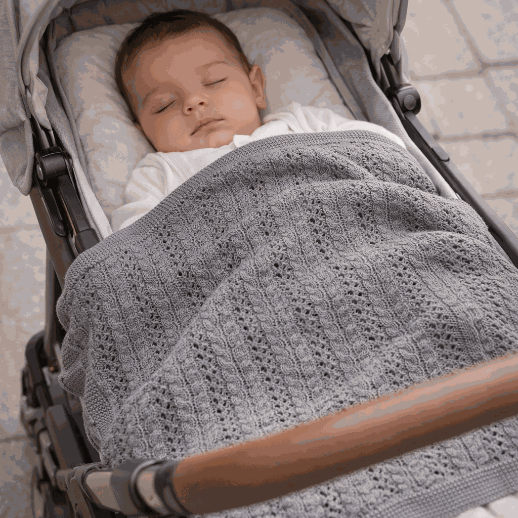 bébé dort dans sa poussette avec sa couverture bebe tricot gris