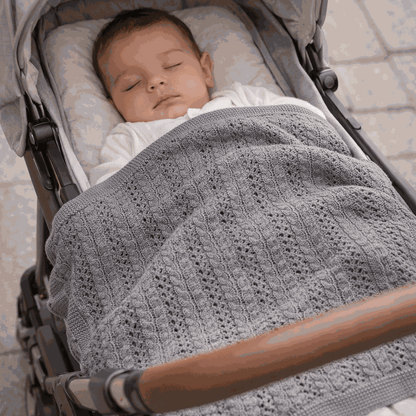 bébé dort dans sa poussette avec sa couverture bebe tricot gris