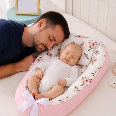 bébé dort dans son reducteur de lit  rose
