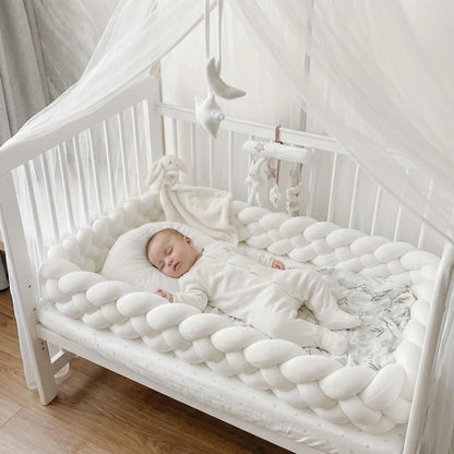bébé dort paisiblement entourer de tresse de lit blanche