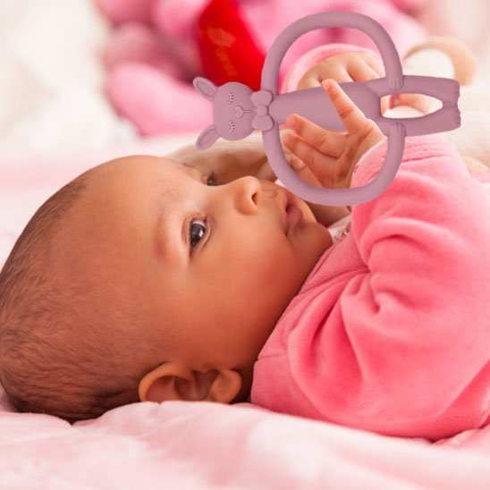 bébé tenant dans ses main anneau de dentition 