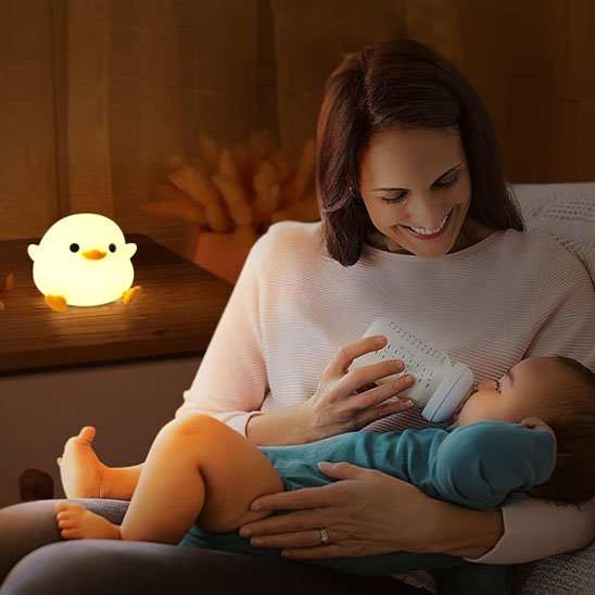 maman donne le biberon a son bébé sous la veilleuse bébé