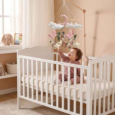 Mobile bébé fille lune rose en feutre suspendu au-dessus du lit avec décorations pastel apaisantes