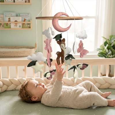 Mobile bébé fille en bois naturel avec figurines lune et papillons roses suspendues au-dessus du lit