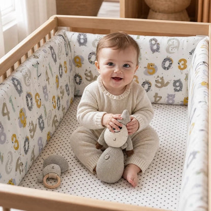 Tour de lit en coton matelassé blanc, orné de motifs gris et jaunes, entourant le lit de bébé