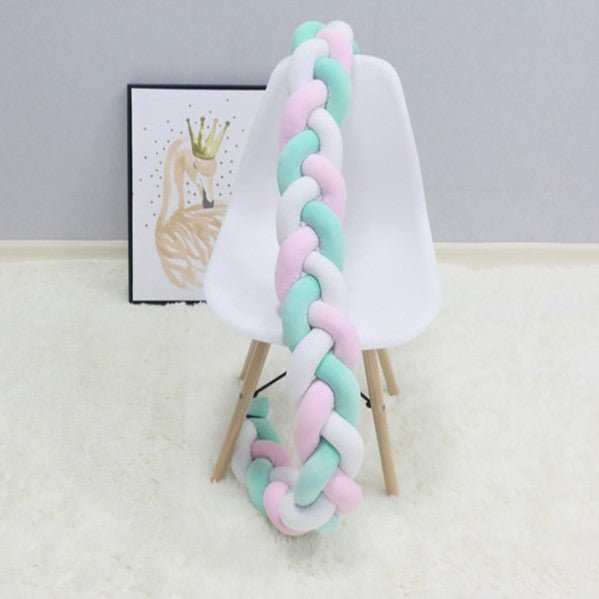 Tresse de lit bébé rose vert blanc sur une chaise 