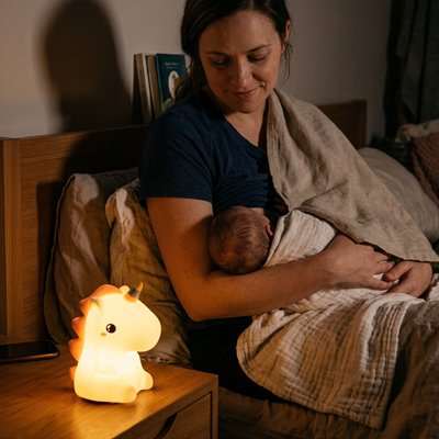 Veilleuse bébé licorne allume pendant que bébé prend le seins